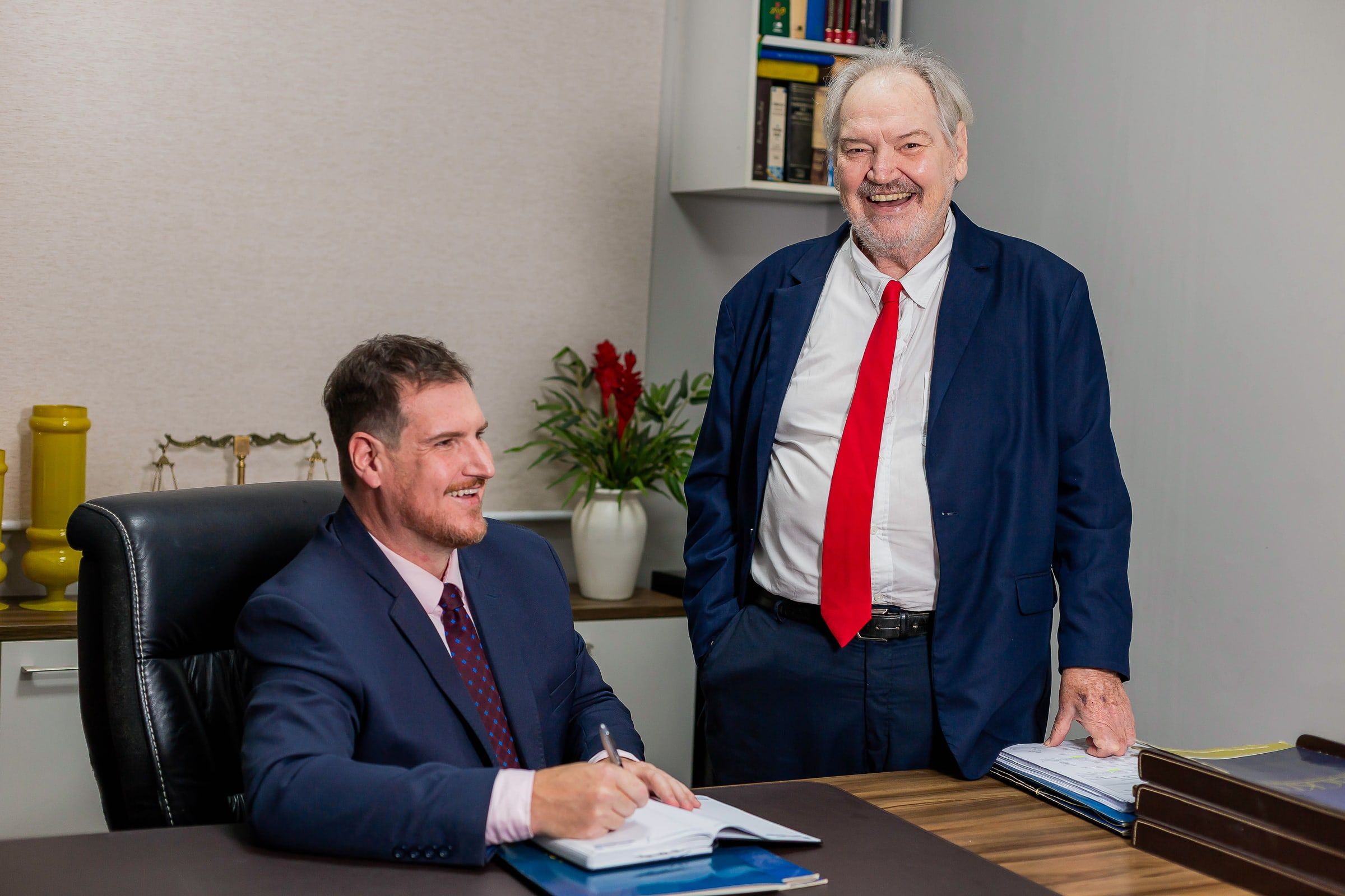 Eduardo Backes faz anotações em sua mesa enquanto Dr. Elstor Backes acompanha
